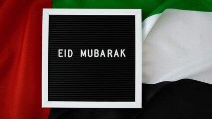 Message text EID MUBARAK - happy holidays waving UAE flag on background concept. Greeting card advertisement. Commemoration Day Muslim Ramadan Blessed holy month public holiday. Patriotism