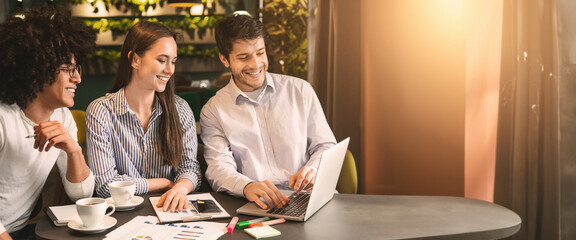 Business colleagues working with presentation at cafe together, looking at laptop during business lunch, copy space
