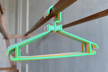 A bunch of colorful plastic hangers hanging on a wooden clothesline
