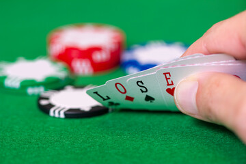 Cards, chips, gambling, poker, blackjack, hand holds cards that spell LOSE