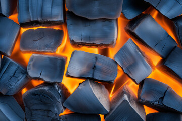 Fototapeta premium Burning charcoal pieces glowing with orange embers in a grill during a summer barbecue