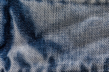 An image of close-up blue denim jeans fabric showing detailed texture with a dark blue color and a...