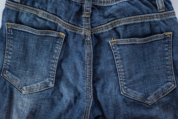 Fototapeta premium Close-up of blue denim jeans texture with a visible pocket, showcasing the fabric's intricate pattern and casual style