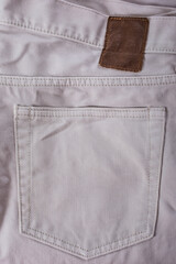Close-up denim fabric with visible pocket and seam, textured and beige in color, perfect for casual...