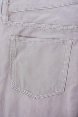 Close-up of beige denim jeans fabric with visible texture and back pocket detail