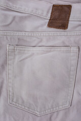 Close-up of beige denim jeans fabric with visible texture and back pocket detail
