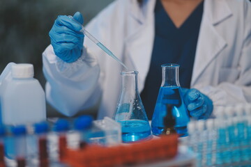 Group of dedicated scientist conduct chemical experiment in medical laboratory, carefully drop precise amount of liquid from pipette into test tube for vaccine drug or antibiotic development. Neoteric