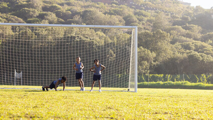 Outdoors, Playing soccer, multiracial boys running and defending goal on school field