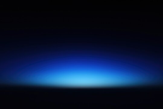 Abstract dark blue background with light glowing on horizon