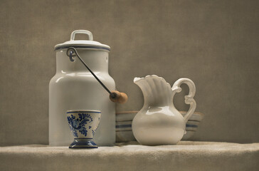 Antique milk can, milk pitcher and bowl arranged on a table