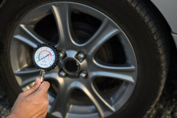 Hand car mechanic holding car tire pressure check equipment tool to checking low tire pressure...