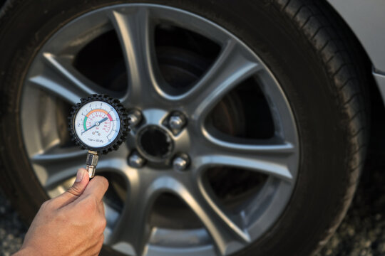 Hand car mechanic holding car tire pressure check equipment tool to checking low tire pressure inflating tires to or refill or air inflate to safety and car care service maintenance inspection.