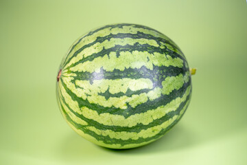 The watermelon and the sliced watermelon piece in green background