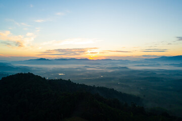 Fototapeta premium Amazing Sunrise or sunset over mountains hills covered with mist, Aerial view landscape drone shot beautiful colorful nature background