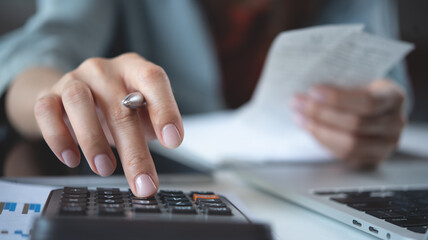 Close-up of businesswoman hands using calculator to calculate company finances, earnings and budget. Business woman calculating monthly expenses, managing budget, business documents, invoices