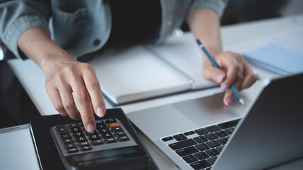 Close up business woman hand using calculator to calculate home finance, accounting with laptop...