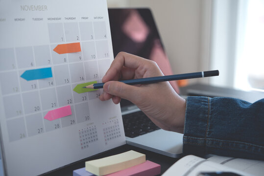 2025 Event planner timetable agenda plan on schedule event. Business woman checking planner, taking note on calendar desk with laptop computer on office table. Calendar event plan, work planning