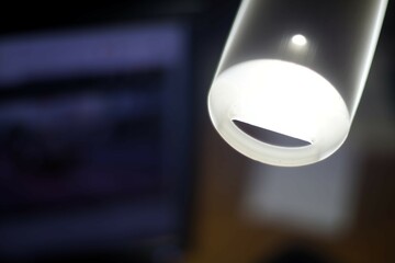 Close-up of a glowing modern LED light bulb in a dimly lit room with blurred background