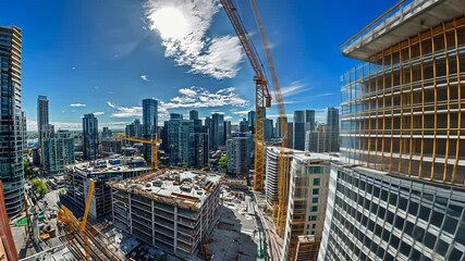 A panoramic view of a construction site with cranes and city skyline in the background.