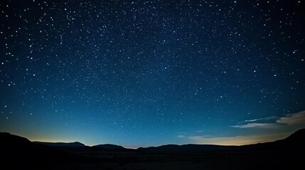 A celestial view of the sky at dawn, with stars still visible as the first light of day begins to illuminate the landscape.