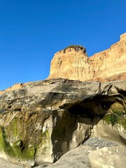 Seaside bluffs in Carlsbad, California, with a clear blue sky and natural arch formation at the base