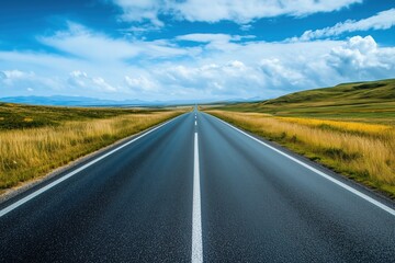Fototapeta premium A straight road stretches toward the horizon under a blue sky with scattered clouds