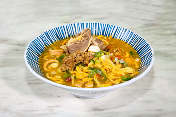 A bowl of spicy tantanmen noodles, topped with ground pork, green onions, and a rich, creamy broth. The bold red chili oil adds heat and flavor to this classic Japanese-Chinese fusion dish.