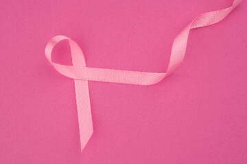 Pink ribbon symbolizing breast cancer awareness on a bright pink background for support
