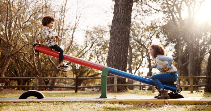 Park, mother and child with seesaw, playground and game with family balance and holiday with parent. Support, love, care with young boy and woman together with joy, bonding and smile in autumn