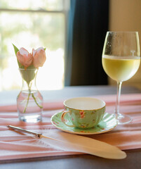 Porcelain teacup and glass of wine on a pastel table setting