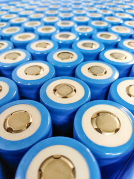 Close-up of blue cylindrical lithium batteries, featuring positive terminal tops, arranged in a precise, repeating grid.