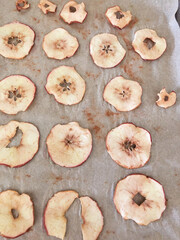 Baked apple slices laid on parchment paper for drying