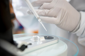 Scientist using pipette with micro volume spectrophotometer in b