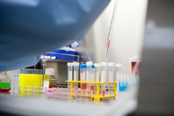 Scientist pipetting into conical cetrifuge tubes in a biotech la