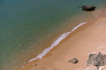 View of sandy beach Prainha Das Pocasby from cliff, among the rocks.