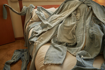 Laundry (blue jeans) tossed on bed
