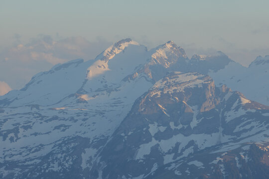 Aerial View from Airplane of Blue Snow Covered Canadian Mountain Landscape in Winter. Colorful Pink Sky Art Render. Tantalus Range near Squamish, North of Vancouver, British Columbia, Canada.