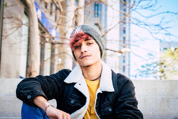Portrait of a rebellious and handsome teenage boy staring directly into the camera with a defiant...