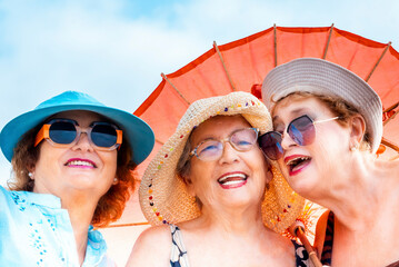 A group of elderly women with a youthful and playful spirit enjoying their summer vacation together, celebrating friendship and retirement. They laugh and have fun outdoors, embracing health and joy