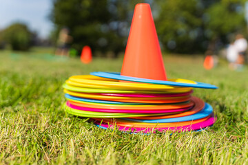 Background with a red cone and colorful game circles in the grass. Children's game concept