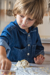 Preschool Kneading Dough With Colorful Sprinkles. A Young Boy Kneads Dough On A Table, Adding Colorful Sprinkles To The Dough In A Bright Kitchen Setting.