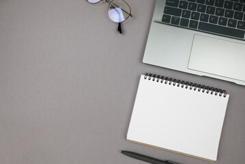 laptop and notepad on gray background, top view, copy space