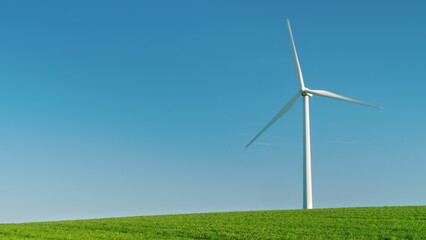 Idyllicistic landscape of a green meadow and a wind generator. Ecology and environment concept.