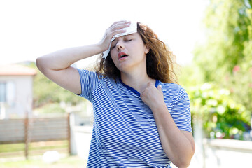 Young woman having hot flash and sweating in a warm summer day