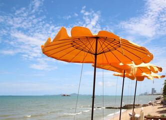 Yellow beach umbrella on blue sky and white clouds