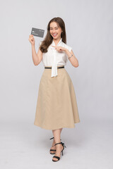 Naklejka premium Smiling young woman holding and pointing to an oversized credit card, promoting financial security and smart banking solutions