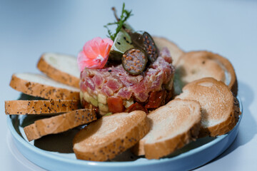 Exquisite Gourmet Tuna Tartare with Artisan Toast on Elegant Blue Plate Adorned with Edible Flower and Capers