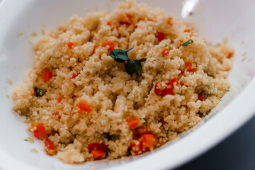 Exquisite Culinary Delight: Creamy Couscous Salad Topped with Fresh Vibrant Vegetables and Aromatic Herbs in Elegant White Bowl