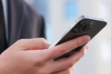 Close up Male hands with smartphone, outdoors. Businessman is typing text messages on mobile phone sitting in the park. Human holds cell phone close up. Man holds mobile phone. Connection concept.