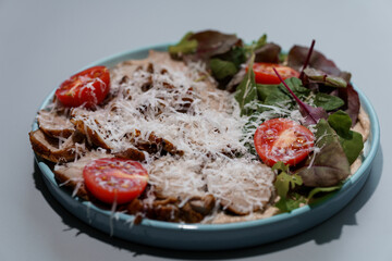 Exquisite Fresh Salad with Crispy Chicken, Juicy Tomatoes, and Shredded Cheese on a Light Blue Plate